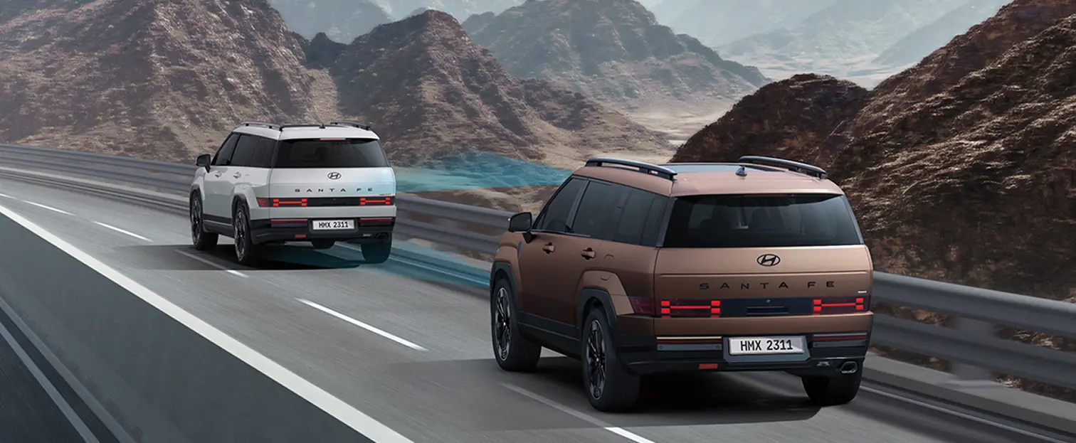 Imagen de dos Santa Fe, una blanca y otra cobre, avanzando por una carretera en una zona mostañosa